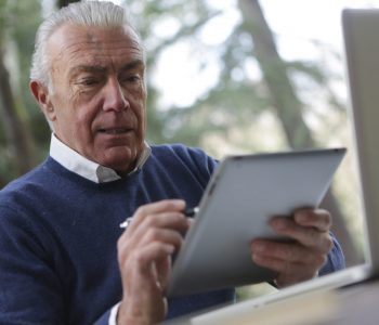 man in blue sweater holding silver ipad