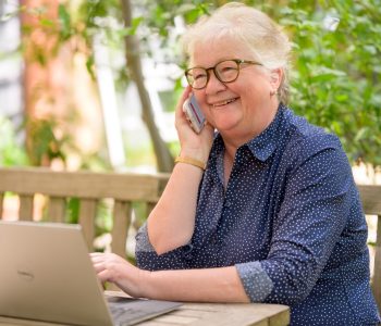 older woman on laptop and speaking on the phone