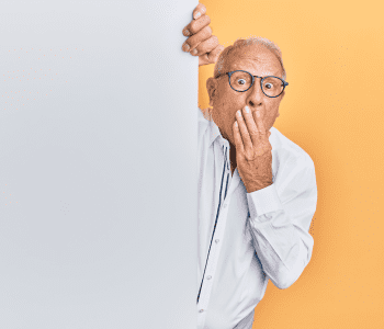 Senior man covering mouth with hand, shocked